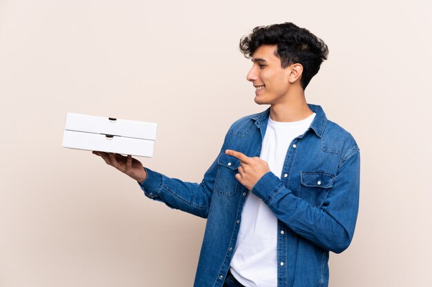 young man holding pizzas boxes over isolated wall