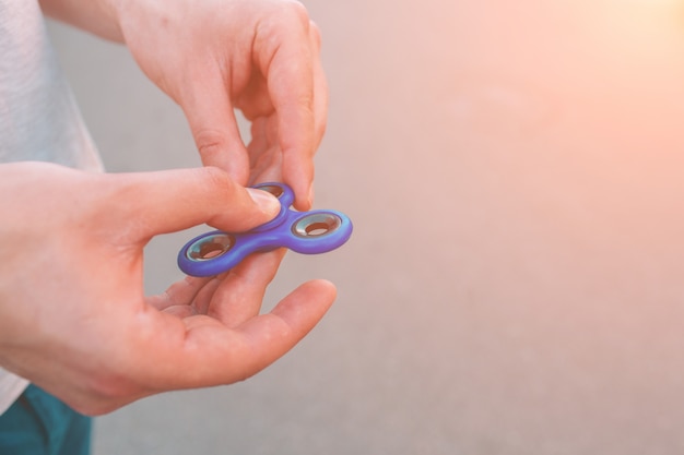 Young man holding and playing with fidget spinner.