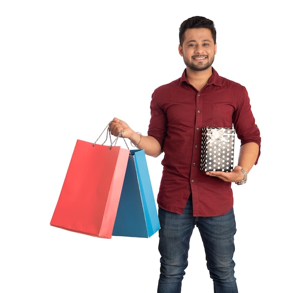 Young man holding and posing with shopping bags and gift boxes on a white background