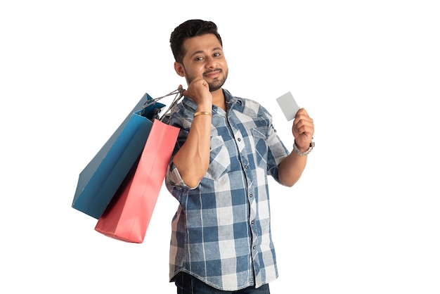 Young man holding and posing with shopping bags with credit or debit card on a white background