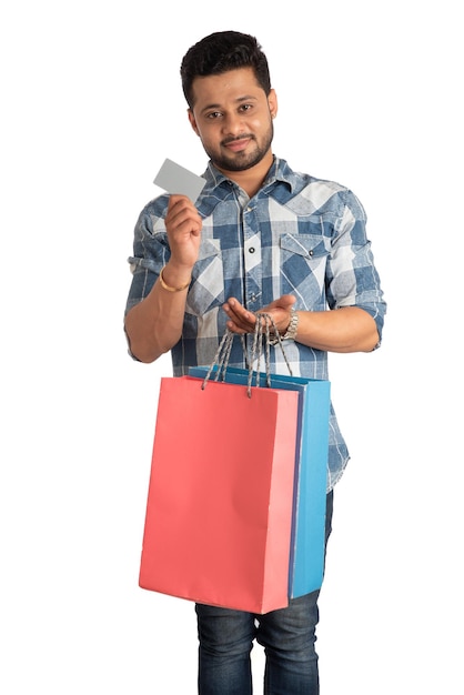 Young man holding and posing with shopping bags with credit or debit card on a white background