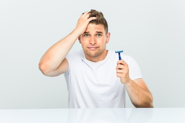 Young man holding a razor blade being shocked, she has remembered important meeting.