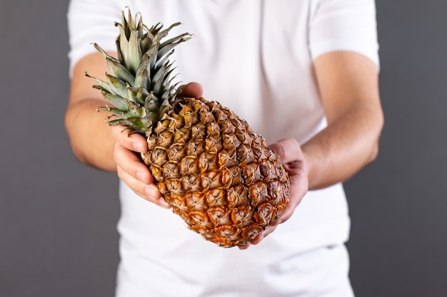 Young man holding a ripe and juicy pineapple isolated