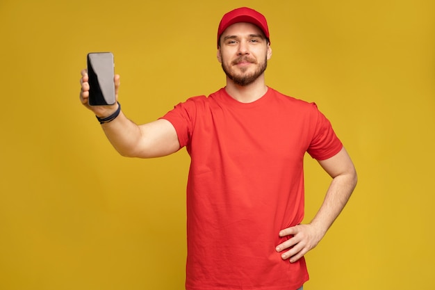 Young man holding smartphone isolated on yellow wall