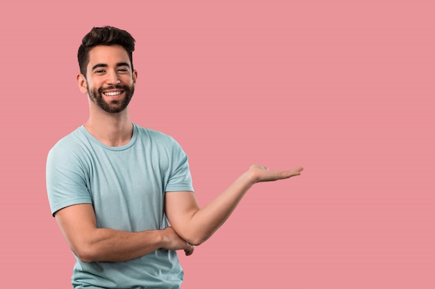 Young man holding something over a pink background