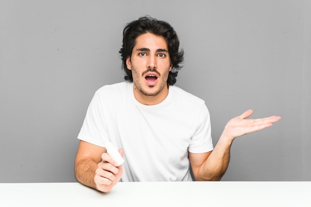 Young man holding a spray nasal impressed holding copy space on palm.