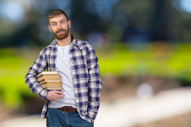 Young Man Holding Stack Of Books