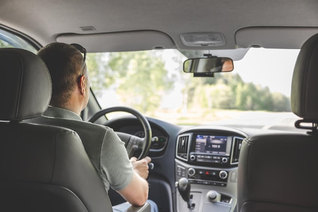 Young man holding steering wheel while driving car road trip\
local travel concept thirst for adventure