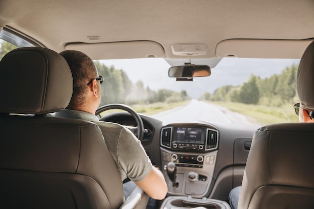 Young man holding steering wheel while driving car road trip\
local travel concept thirst for adventure