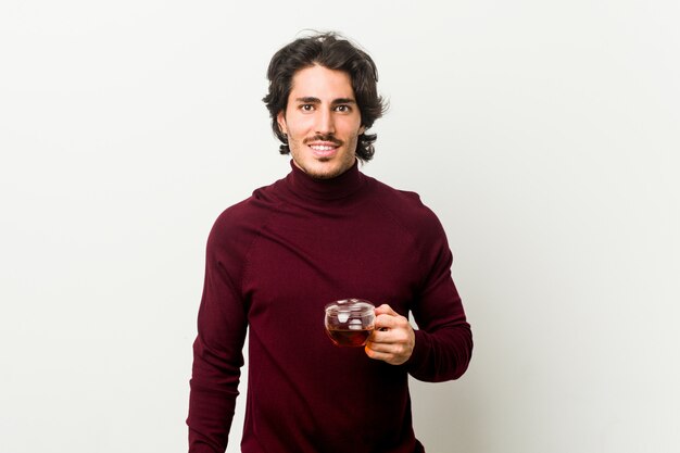 Young man holding a tea cup happy, smiling and cheerful