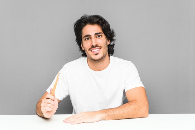 Young man holding a toothbrush happy, smiling and cheerful.