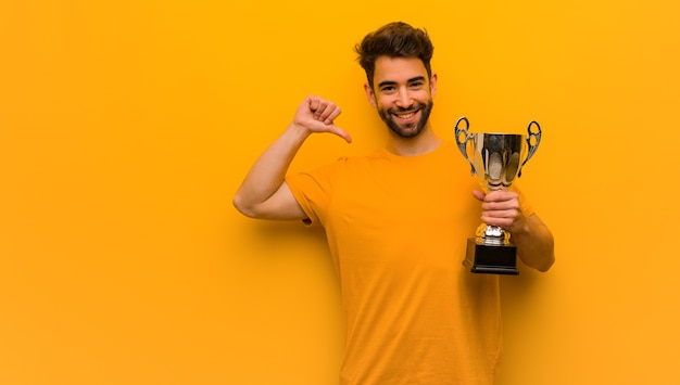 Young man holding a trophy pointing fingers, example to follow