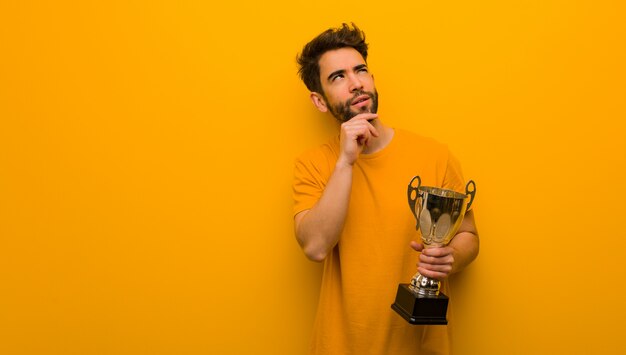 Young man holding a trophy thinking about an idea