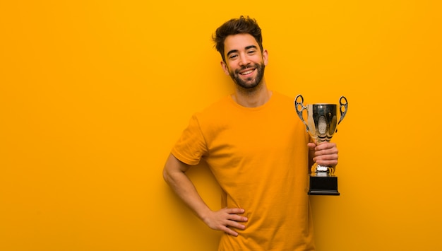 Young man holding a trophy with hands on hips