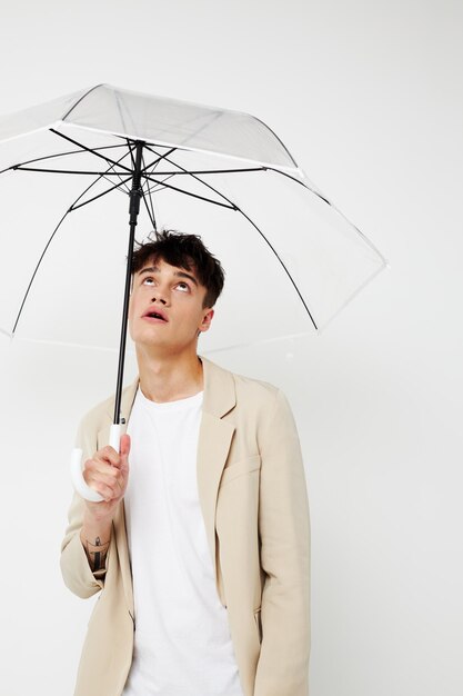 A young man holding an umbrella in the hands of posing fashion light background unaltered