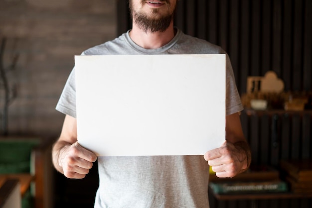 A young man holding a white frame with copy space for text