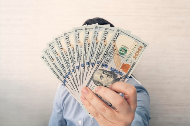 A young man holds 1000 dollars in his hands on a white background in the office