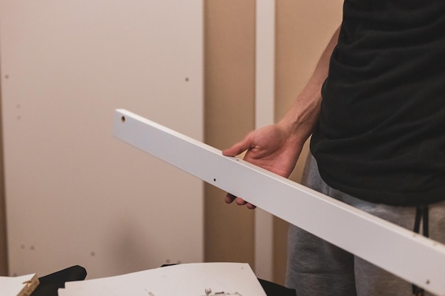 A young man holds a board from the closet in his hands