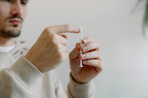 A young man holds a medicine in a syringe in his hands