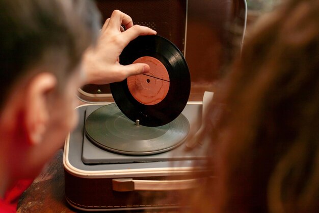 若い男がレコード盤をターンテーブルで手に持っている