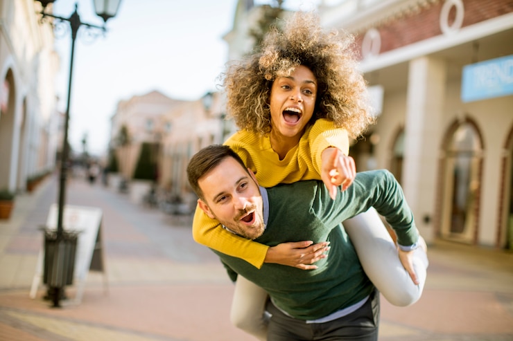 Photo young man holds a young woman on his back and entertaining themselvs