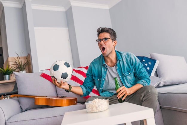 Young man home alone watching soccer 