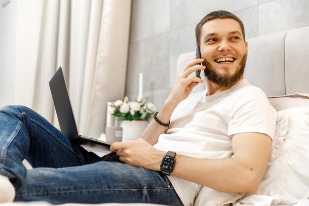 Young man at home on the couch talking on the phone side view looking away