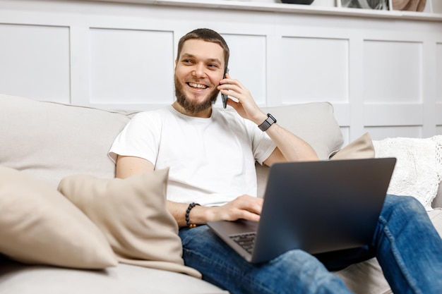 Young man at home on the couch talking on the phone side view looking away