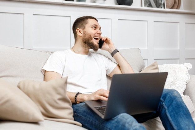 Young man at home on the couch talking on the phone side view looking away