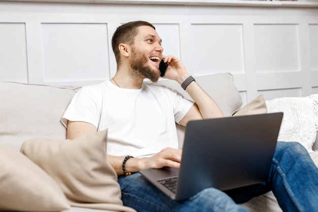 Young man at home on the couch talking on the phone side view looking away