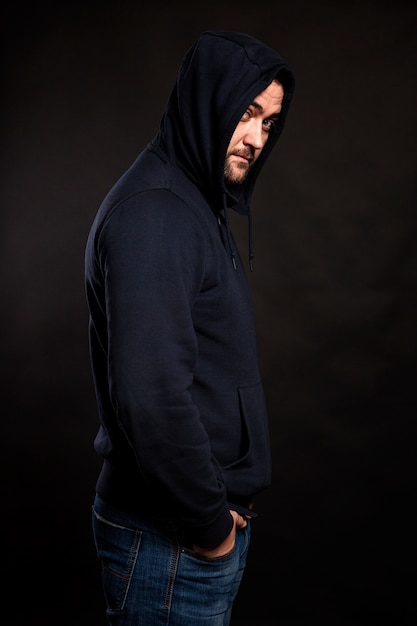 A young man in a hoodie and hood on black 