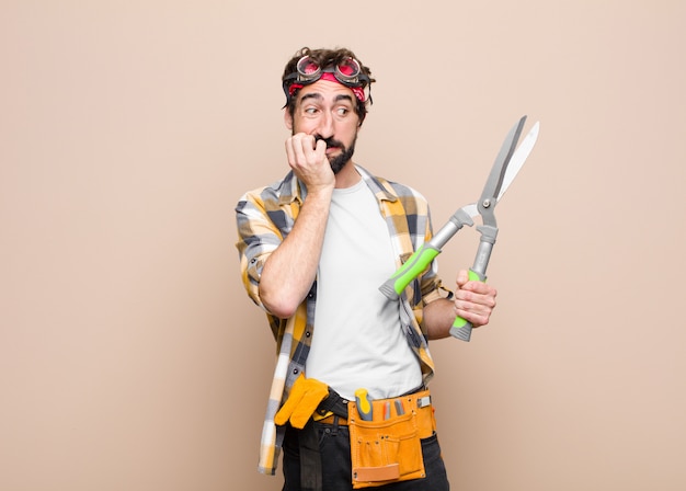 Young man housekeeper with a scissors on wall