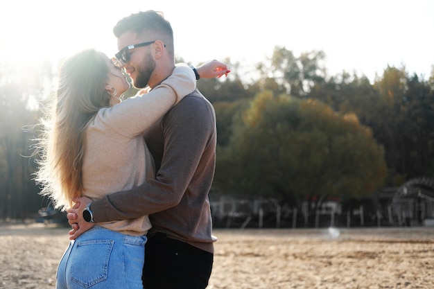 A young man hugs a girl by the waist boy and girl look at each\
other and are about to kiss