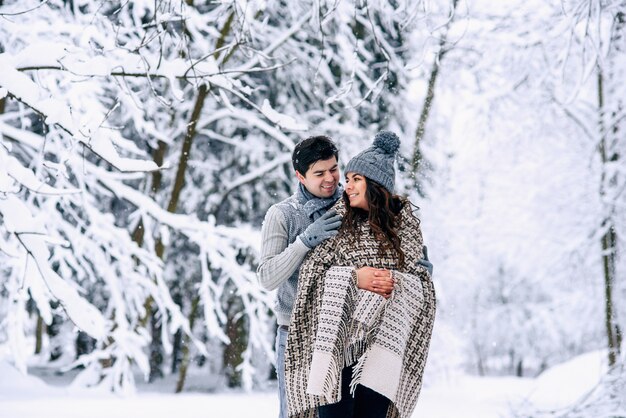 Young man hugs tenderly his beautiful pregnant wife covered in warm plaid