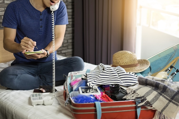 Young man hurring up to meeting and talking by phone and taking notes packing 