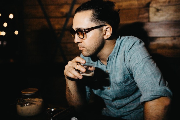 사진 셔츠를 입은 젊은 남자가 카페에서 차를 마시고 있다.
