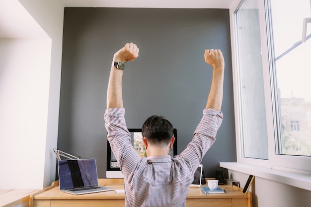 写真 自宅のコンピューターに取り組んでいるシャツの若い男