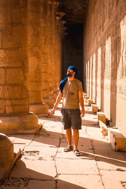 Фото Молодой человек в синем тюрбане идет по колоннам храма эдфу