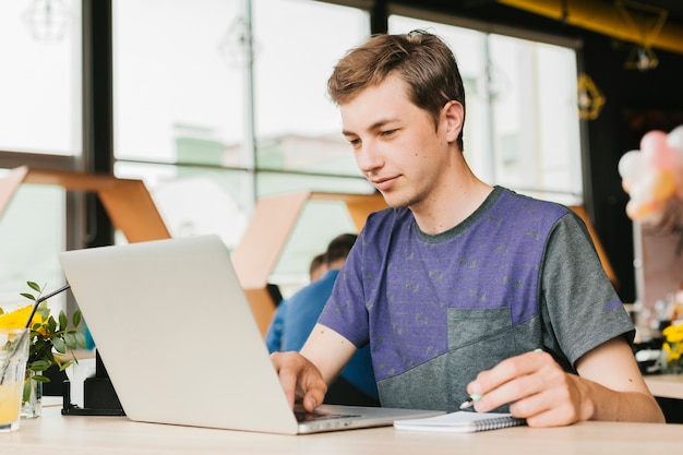 Фото Молодой человек в кафе работает на ноутбуке