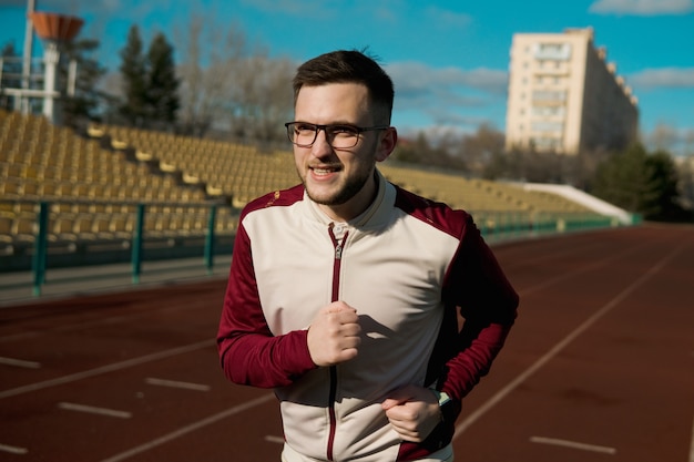 写真 スタジアムでジョギングメガネの若い男