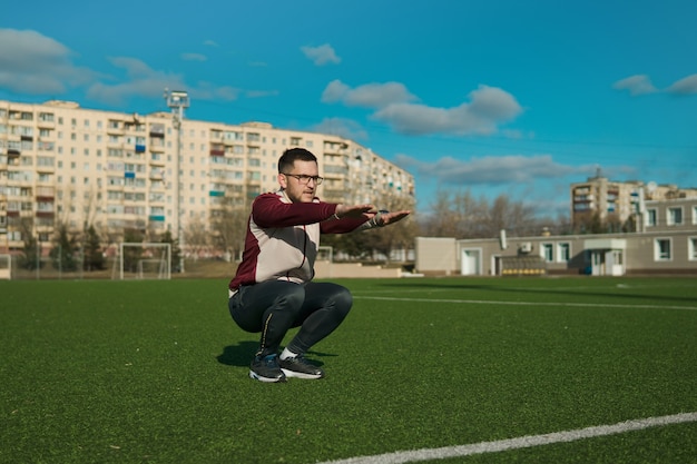 写真 スタジアムでストレッチ眼鏡をかけた若い男