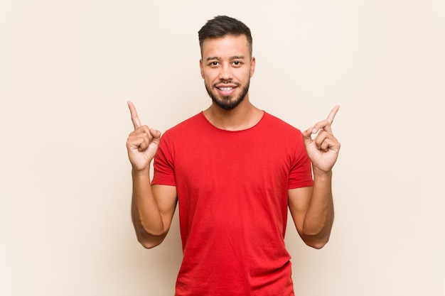 Young man indicates with both fore fingers up showing a blank space.