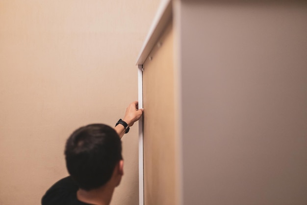 Photo a young man installs rivets on a wardrobe