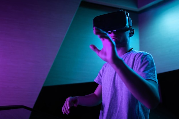 Young man interacting in a digital world using virtual reality headset with motion tracking tech