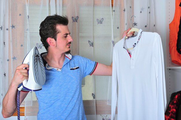 Young man ironing a steamed shirt.