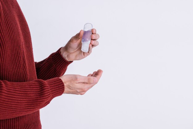 Young man is applying disinfectant gel to his hands to prevent infection on a white background. Concept of coronavirus (covid-19) and virus transmission