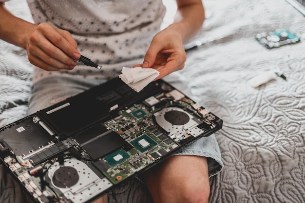 A young man is changing the thermal paste on a laptop