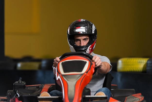 Молодой человек за рулем автомобиля GoKart со скоростью на игровой площадке Гоночный трек Go Kart - популярный вид автоспорта