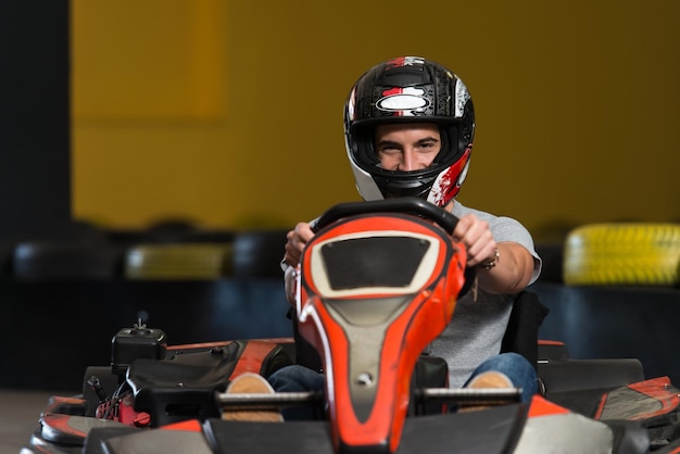 Молодой человек за рулем автомобиля GoKart со скоростью на игровой площадке Гоночный трек Go Kart - популярный вид автоспорта