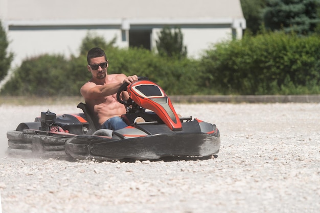 Il giovane sta guidando l'auto di gokart con velocità in una pista da corsa del parco giochi go kart è un popolare sport motorio per il tempo libero